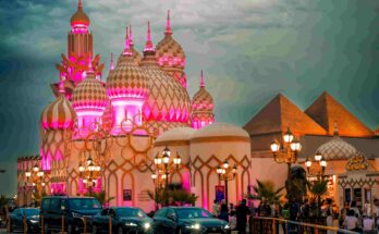 Global Village Dubai at night with pink and gold illuminated domes, Egyptian pyramids, and street lamps — GlanceAsia Travel Guide