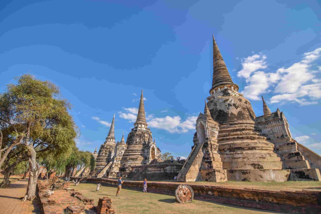 Tourists walking among large ancient stupas and historical ruins at Ayutthaya Thailand on a sunny day