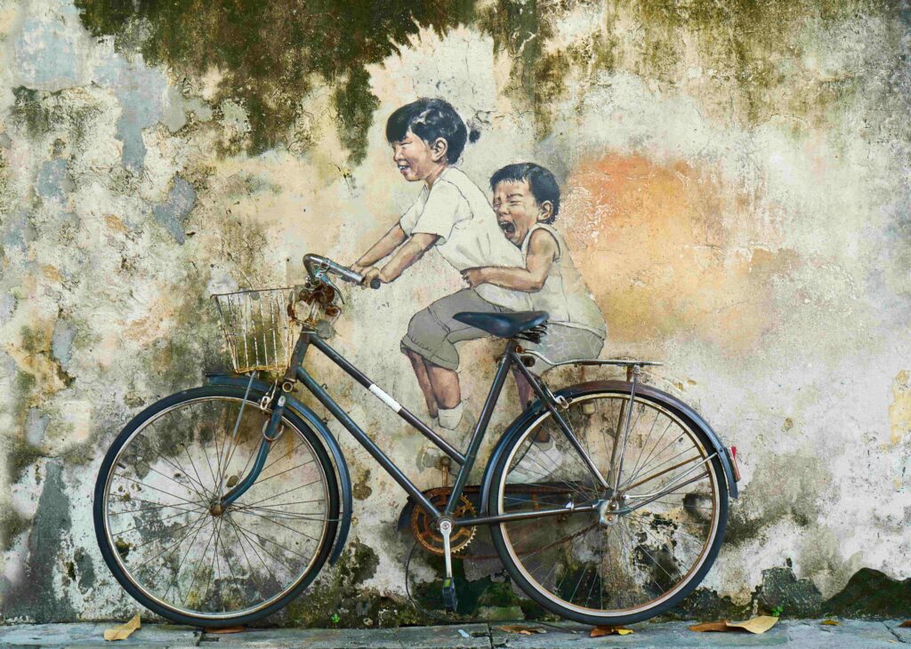Famous Ernest Zacharevic street art mural of two children riding a bicycle on a crumbling wall in George Town, Penang, Malaysia