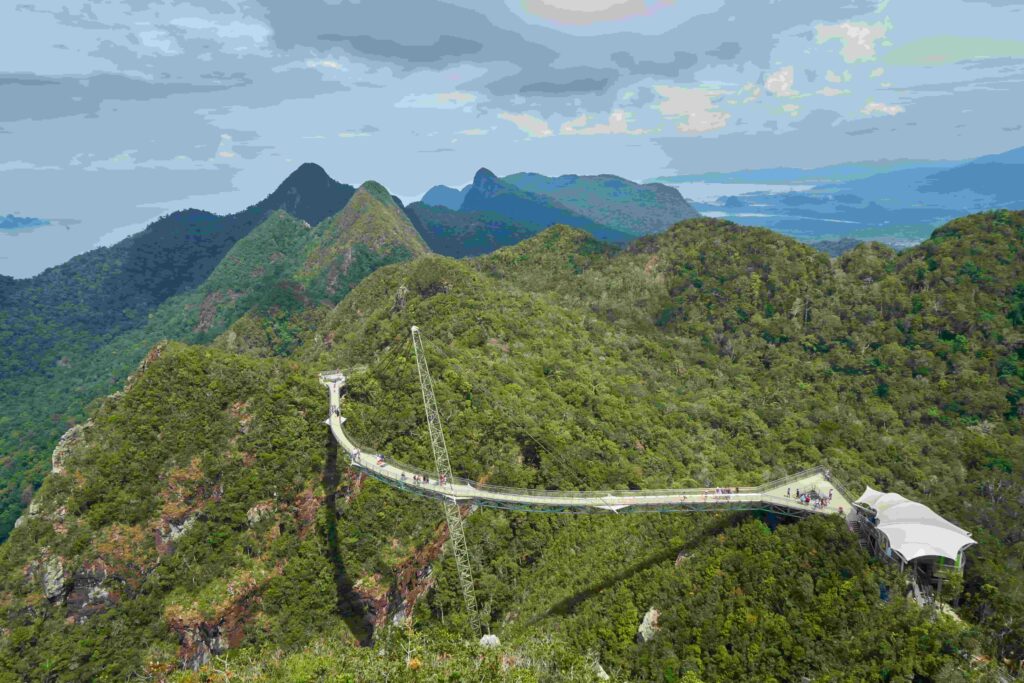 Aerial view of Langkawi Sky Bridge curving across mountain ridge with surrounding green rainforest mountains and Andaman Sea in background Malaysia