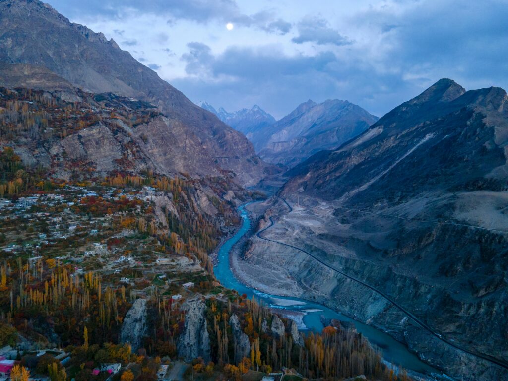 "Stunning aerial view of Hunza Valley, Pakistan, during autumn featuring the turquoise Hunza River and golden foliage against rugged mountains."