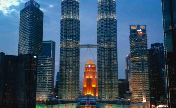 Aerial view of Petronas Twin Towers and Kuala Lumpur skyline at blue hour with city lights glowing