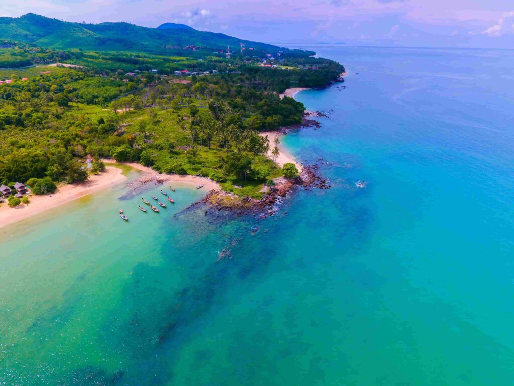 Aerial view of Yona Beach Koh Lanta Thailand with turquoise water longtail boats and lush green coastline