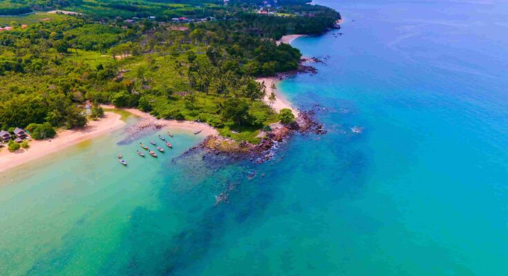 Aerial view of Yona Beach Koh Lanta Thailand with turquoise water longtail boats and lush green coastline
