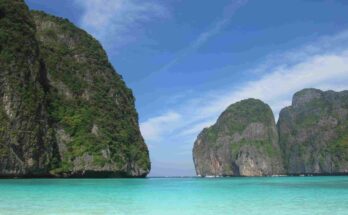 The iconic entrance of Maya Bay featuring clear blue skies and vibrant neon-turquoise water in Southern Thailand