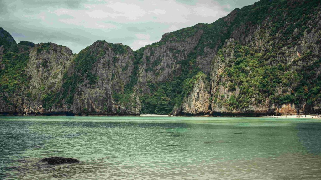 Dramatic green limestone cliffs surrounding the calm turquoise waters of Maya Bay beach in Thailand