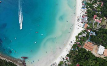 Aerial view of Long Beach on Perhentian Kecil, Malaysia, showing turquoise waters, white sand, and traditional boats anchored along the shore. Perhentian Islands
