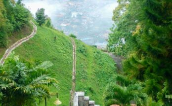 Penang Hill funicular railway tunnel entrance with steep hillside tracks and misty George Town cityscape visible below, Malaysia