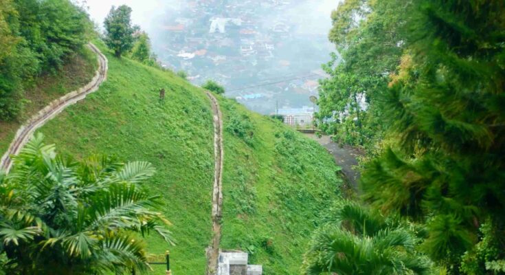 Penang Hill funicular railway tunnel entrance with steep hillside tracks and misty George Town cityscape visible below, Malaysia