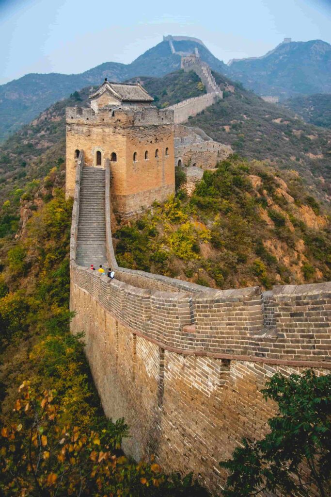 Ancient brick watchtower on the Great Wall of China with steep stone steps and mountain views in autumn