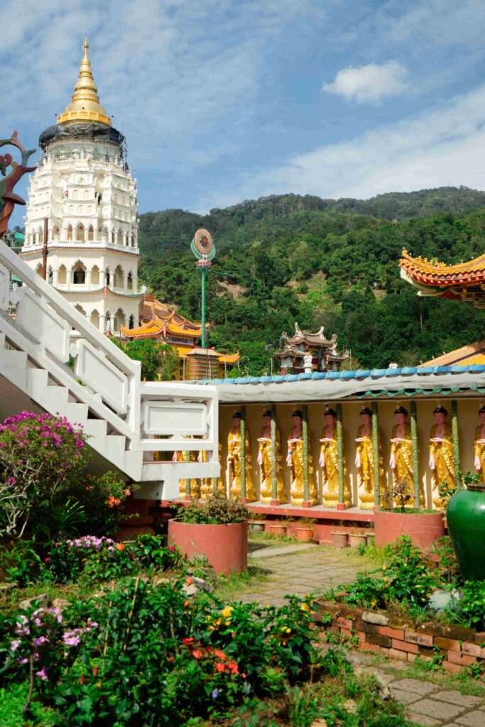 Kek Lok Si Temple golden pagoda and Buddha statues with Penang Hill's forested slopes rising in the background, Air Itam, Penang hills