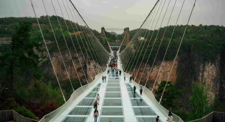 Tourists walking on the Zhangjiajie Grand Canyon Glass Bridge suspended 300 metres above the valley in Hunan China