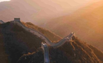 Great Wall of China winding through mountain ridges at golden sunset near Beijing