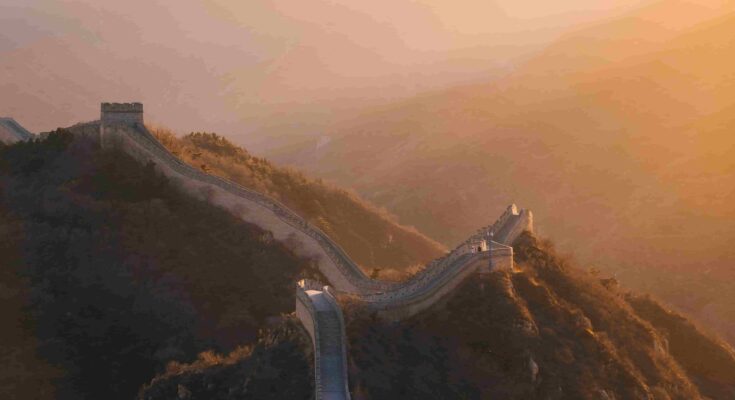 Great Wall of China winding through mountain ridges at golden sunset near Beijing