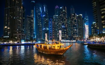 Traditional dhow cruise boat lit up at night in front of Dubai Marina skyscrapers