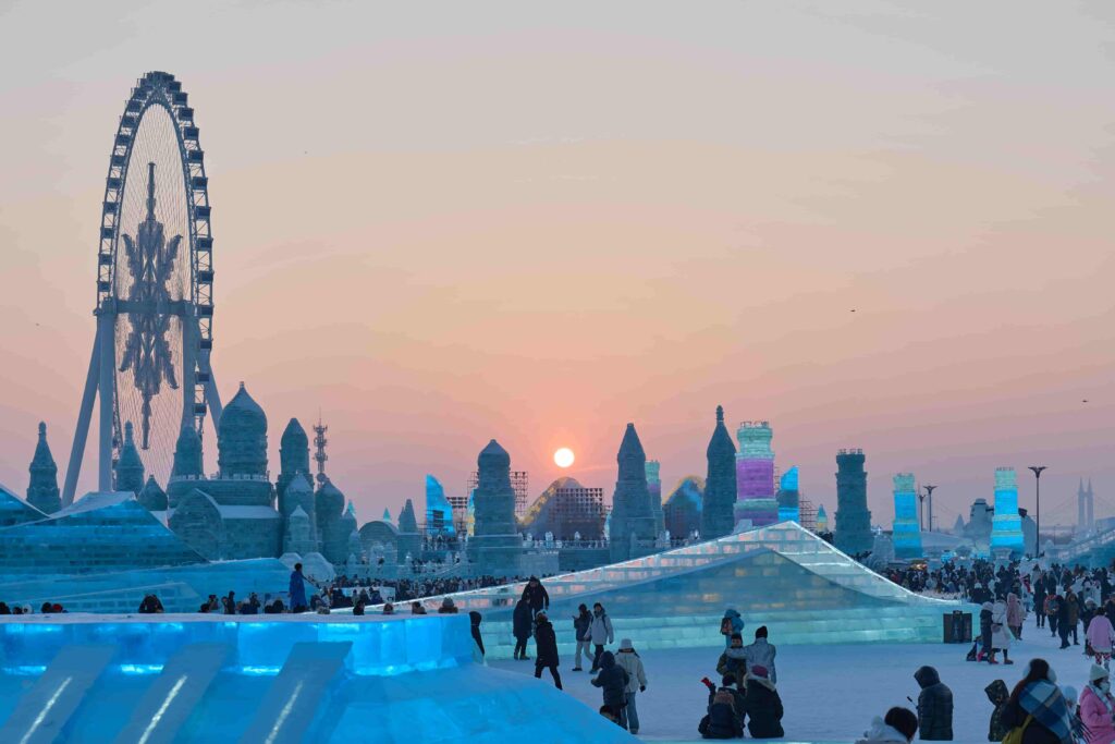 Sunset view of Harbin Ice and Snow World with Ferris wheel and ice sculptures