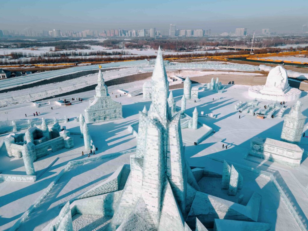 Aerial view of Harbin Ice and Snow World ice sculptures with city skyline in the background