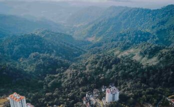 Aerial view of Genting Highlands resort towers surrounded by misty mountains and clouds