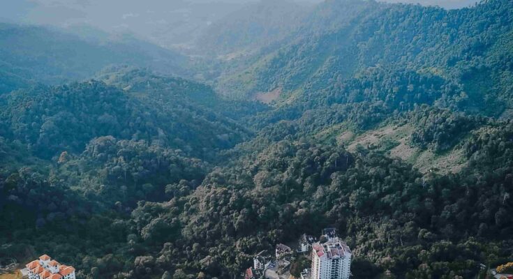 Aerial view of Genting Highlands resort towers surrounded by misty mountains and clouds