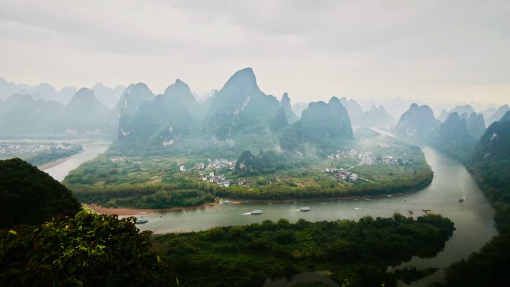 Tourist boats cruising Li River near Xingping in misty morning light
